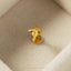 A single gold-colored earring is displayed on a white surface.
