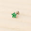 A silver earring with a green gemstone in the center, resting on a beige background.