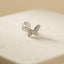 A silver butterfly-shaped earring is resting on a light-colored surface.