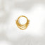A gold-colored ring with a chain attached to it, resting on a white surface.