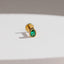A gold earring with a green gemstone is shown against a white background.
