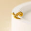 A small golden bird-shaped earring is perched on a white surface.