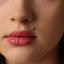 A close-up of a person's face, focusing on their lips and a small gold earring in their ear.