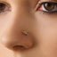A close-up of a person's nose with a small gold-colored nose ring with a diamond-like stone on it.