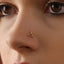 A close-up of a person's face, focusing on their nose and the small gold nose ring with a scissor-like design.