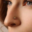 A close-up of a person's nose and face, with a small gold-colored octopus-shaped nose ring visible.
