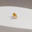 A gold earring with a clear gemstone is shown against a white background.
