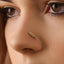 A close-up of a person's face, focusing on their nose and the gold feather nose ring.