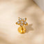 A gold-colored diamond-encrusted earring with a star-shaped design, placed on a light-colored surface.