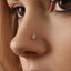A close-up of a person's face, focusing on their nose and the small gold nose ring with a diamond-like stone.