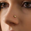 A close-up of a person's face, focusing on their nose and the small gold shell nose piercing.