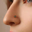 A close-up of a person's nose with a small, green gemstone nose ring.