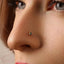 A close-up of a person's face, focusing on their nose and the small, triangular-shaped nose piercing.