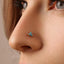 A close-up of a person's nose with a small turquoise-colored stone stud or piercing.