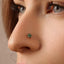 A close-up of a person's nose with a small green gemstone nose ring.