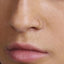 A close-up of a person's nose and mouth, with a gold-colored nose ring visible.