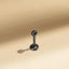 A small, shiny metal object resembling a ball or pin is positioned on a light-colored surface.