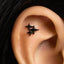 a close-up view of a person's ear, with a small black star-shaped earring or stud protruding from the earlobe.