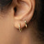 A close-up view of a person's ear with two gold hoop earrings attached.