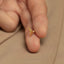 a person's hand holding a tiny gold ring