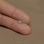 a person's hand holding a tiny silver bow ring