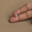 A person's hand holding a small silver earring on the index finger.