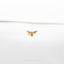 a small gold bird brooch sitting on top of a white surface