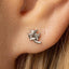 A silver earring in the shape of a small bat or flying insect is visible in the person's ear.