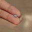a person's hand holding a small silver flower ring