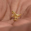 A small gold-colored dinosaur figurine is being held in a person's hand.