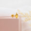 a pair of yellow gold earrings on a pink box