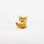 A small golden figurine of a raccoon sitting on a white surface.