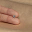 a person's hand holding a small diamond ring