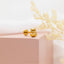 a pair of gold owl earrings sitting on top of a pink box