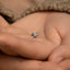 a tiny bowknoted ring sits in the palm of someone's hand
