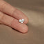 a person's hand holding a tiny heart shaped ring