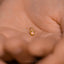 a tiny gold ring with a pink heart on it
