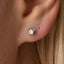 A silver earring with the number 12 on it is visible in the image.