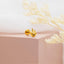 a pair of gold earrings sitting on top of a pink box