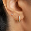 A close-up view of a person's ear adorned with two gold hoop earrings, one of which has a small diamond accent.