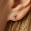 A small silver earring with a hammer-shaped design is visible in the image.