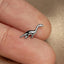 a small silver dinosaur brooch sitting on top of a person's finger