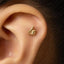 A gold-colored earring with a thumbs-up symbol on it is visible in the image.