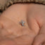 a tiny silver bird pin sitting on top of a person's hand