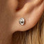 A close-up view of a person's ear with a small silver earring in the earlobe.