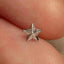 a person's hand holding a tiny silver star ring