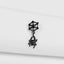 A black metal earring with a spider design hangs against a white background.