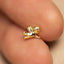 A small, shiny gold-colored angel figurine is being held between two fingers.