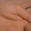a person's hand with a tiny diamond ring on it