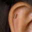 A gold-colored metal earring is visible in the ear.